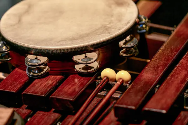 Image of tambourine and drumsticks lie on a wooden xylophone