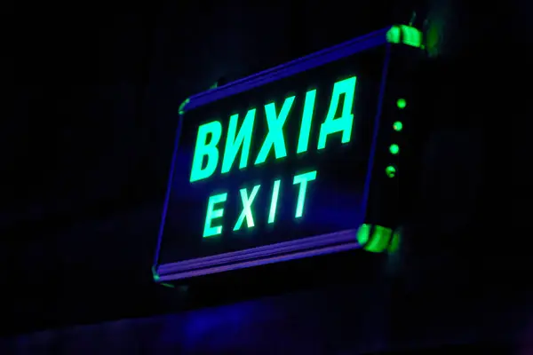 Image of a glowing exit sign above the doors in the hall