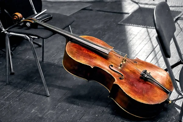 An image of a string musical instrument of a symphony orchestra the cello lies on the theater stage