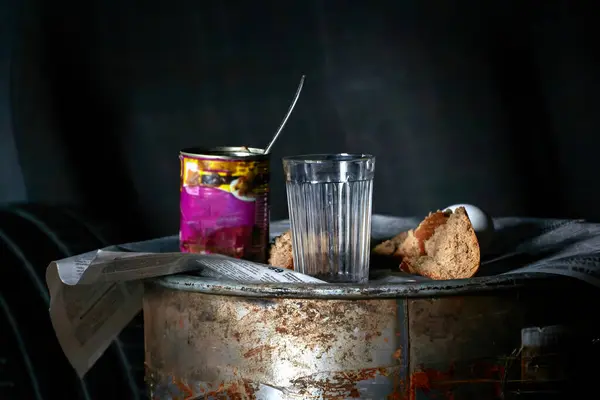 開いた錫の缶の近くの空のガラスおよびパンの破片のイメージ錆ついた樽で ストック写真