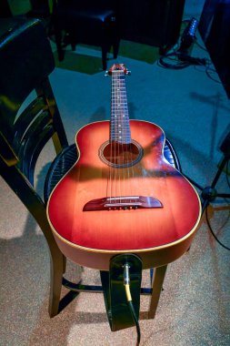 Sahnede duran bir sandalyede duran akustik gitarın görüntüsü