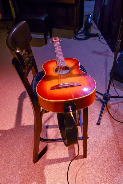 Sahnede duran bir sandalyede duran akustik gitarın görüntüsü