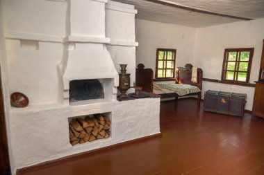 Sobası ve ahşap mobilyası olan geleneksel bir Ukrayna köy kulübesinin resmi.