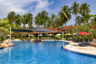 Malezya, Langkawi, Kasım 2022: Langkawi 'deki Pelangi Plaj Oteli' nin bölgesinde yüksek palmiye ağaçları olan güzel bir bahçede yüzme havuzu.