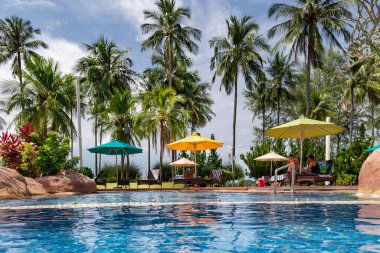 Malezya, Langkawi, Kasım 2022: Langkawi 'deki Pelangi Plaj Oteli' nin bölgesinde yüksek palmiye ağaçları olan güzel bir bahçede yüzme havuzu.