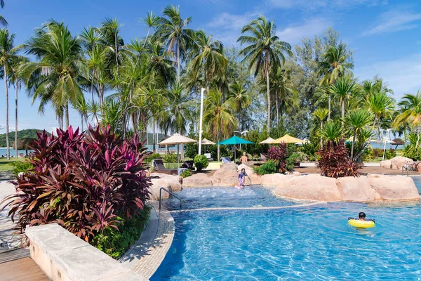 Malezya, Langkawi, Kasım 2022: Langkawi 'deki Pelangi Plaj Oteli' nin bölgesinde yüksek palmiye ağaçları olan güzel bir bahçede yüzme havuzu.