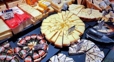 LATVIA, RIGA, FEBRUARY, 2023:  Showcase in grocery store with huge selection of various delicacies cheeses in different packages, shapes, types and manufacturers. Concept of food properly, gastronomic delights.