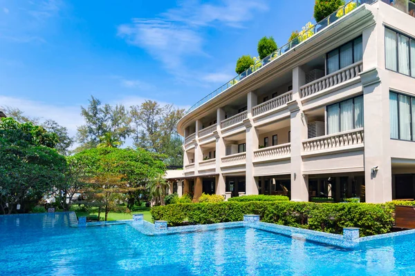 Modern architecture of a multi-storey hotel with a glass elevator and a swimming pool with clear water for sports and leisure in Phuket, Thailand