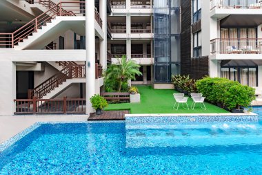 Modern architecture of a multi-storey hotel with a glass elevator and a swimming pool with clear water for sports and leisure in Phuket, Thailand