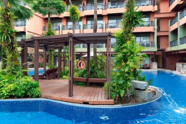 THAILAND, PHUKET, FEBRUARY, 2023: Swimming pool among a beautiful garden with tall palm trees on the territory of Patong Merlin Hotel in Phuket, Thailand