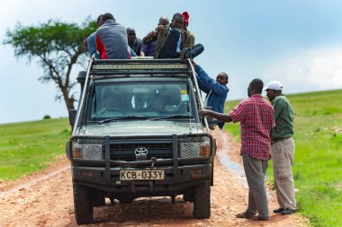 AFRICA, KENYA, MAYIS 2016 - Afrikalı bir grup adam Kenya, Afrika 'daki savanada taşınmak üzere cipin tepesinde oturuyorlar