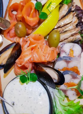 Dilimlenmiş somon, midye, tütsülenmiş balık tabağı, yakın plan tuzlu ringa balığı. Bitkilerle ve limon dilimleriyle süslenmiş. Kıymetli lezzetli deniz balığı türlerinden soğuk meze..