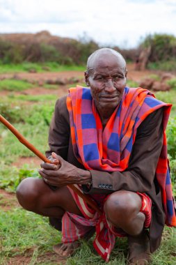 AFRICA, KENYA, MAYIS, 2016 - Masai kabile köyünde yeşil bir çayırda oturan yaşlı Afrikalı erkeklerin portresi. Masailer güney Kenya ve kuzey Tanzanya 'da yaşayan Nilotik bir etnik gruptur..