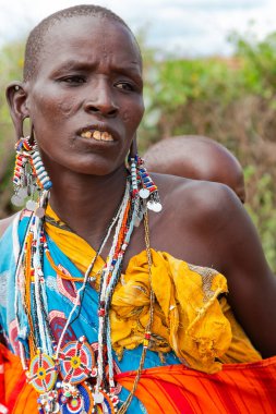 AFRICA, KENYA, MAYIS, 2016 - Masai Mara kabilesinin geleneksel çocuklu bir kadın portresi Kenya, Afrika 'da boncuklu mücevherler satıyor