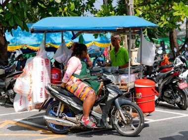 THAILAND, FEBRUARY, 2023: Bir motosikletli yiyecek satıcısı, Tayland 'ın Phuket adasının en ünlü turistik bölgesi olan Patong plajı yakınlarında yiyecek satıyor..