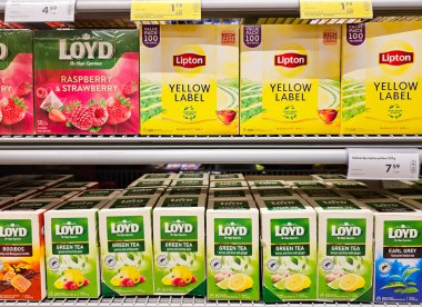 LATVIA, RIGA, APRIL, 2023: Bir dizi sarı renkli Lipton çayı süpermarket rafında Loyd yeşil çayı. Perakende sektörü. Raflarda satılık çeşitli çay paketleri.