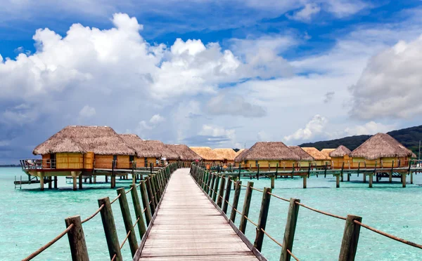Overwater bungalows stretching and a wooden bridge out across the lagoon in Bora Bora island, Tahiti. Romantic honeymoon destination.