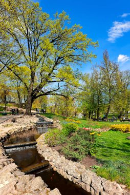 LATVIA, RIGA, APRIL, 2023: İnsanlar Riga şehir merkezinde yer alan ilkbahar başlarında Bastion Hill boyunca yürüyüp dinleniyorlar. Bastion Hill Riga 'nın merkezindeki en romantik yerlerden biridir..