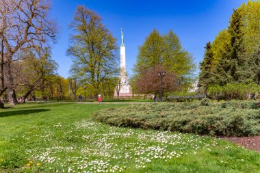 LATVIA, RIGA, MAYIS, 2023 - Riga sakinleri ve konukları Riga, Letonya 'daki Özgürlük Anıtı yakınlarındaki yeşil çimlerde çiçek açan bahar parkında dinleniyor