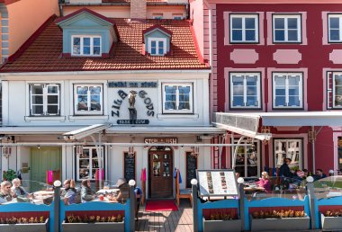 LATVIA, RIGA, MAYIS, 2023: Turistler Livu Meydanı 'ndaki en ünlü ve güzel meydanlardan birinin açık verandasında yemek yiyorlar..