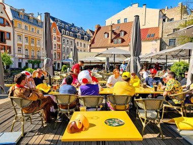 LATVIA, RIGA, MAYIS, 2023: 2023 Buz Hokeyi Dünya Şampiyonası turistleri ve hayranları Riga Old Town, Letonya 'daki kafelerin açık verandasında bira içiyorlar. Riga şehir tarihi merkezi UNESCO 'nun Dünya Mirasları Alanıdır.
