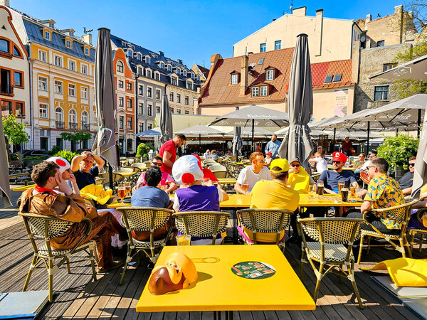 LATVIA, RIGA, MAY, 2023: Tourists and fans of the Ice Hockey World Championship 2023 drink beer on the open veranda of cafes in Riga Old Town, Latvia. Riga city historical centre is a UNESCO World Heritage Site