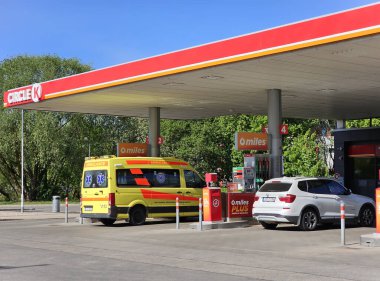 LATVIA, RIGA, 15 Mayıs 2023: CIRCLE K benzin istasyonu ve Riga, Letonya 'da yakıt ikmali yapılan sarı bir ambulans.