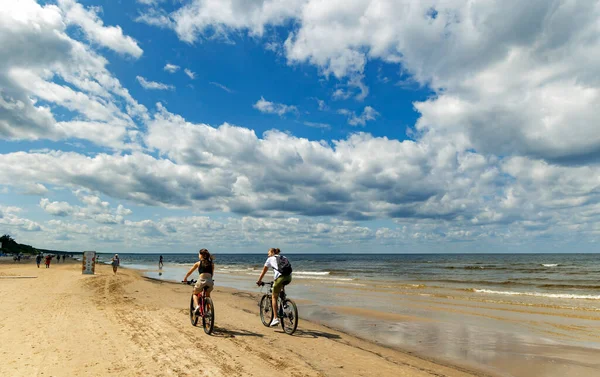 拉特维亚 朱尔马拉 07年7月 2023年7月 一对骑自行车的夫妇在天空的背景下沿着波罗的海海岸骑着卷云 骑自行车在海上行走 — 图库照片