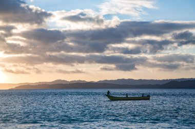 Hindistan Okyanusu, Batı Papua, Endonezya 'daki Raja Ampat adalarının üzerinde gün batımında yalnız bir tekne.