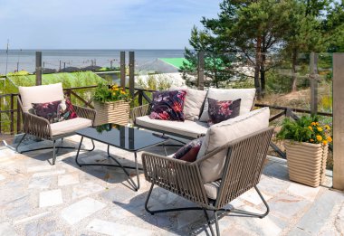 LATVIA, JURMALA, 20, JULY, 2023: Kahve masası ve Baltık Denizi kıyısına bakan yumuşak hasır mobilyalı bir restoranın açık verandası, Jurmala. Letonya
