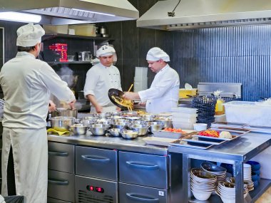 Letonya, Riga, 03 Ağustos 2023 - Restoran şefleri Riga, Letonya 'da bir Asya restoranının modern mutfağında çalışıyorlar