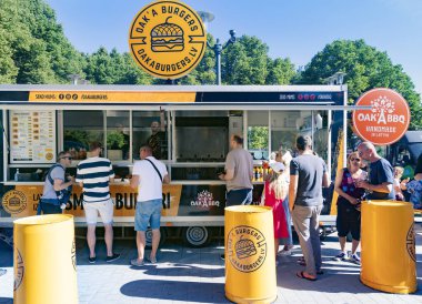 LATVIA, RIGA, 15, AUGUST, 2023: People waiting in line for hamburgers at the food truck on Riga Burger Festival at the Esplanade Park in Riga. Latvia. clipart