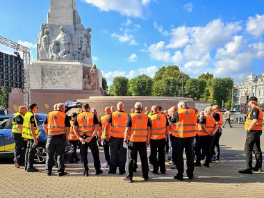 Letonya, Riga, 23 Eylül 2023: Letonya 'daki Özgürlük Anıtı yakınlarındaki bir toplantıda turuncu yelekli bir güvenlik ekibi