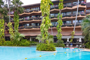 THAILAND, PHUKET, 18, FEBRUARY, 2023: Tayland, Phuket 'te Patong Merlin Oteli' nin bölgesinde uzun palmiye ağaçları olan güzel bir bahçede yüzme havuzu