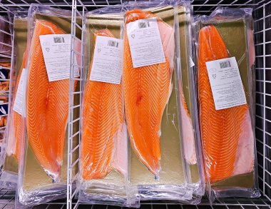 Lidl süpermarketindeki buzdolabında elektrikli süpürgeyle taze somon filetosu kes, Riga. Letonya