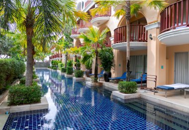THAILAND, PHUKET, 18, FEBRUARY, 2023: Yüzme havuzu Phuket Graceland tatil köyü ve Patong, Tayland 'daki spa otelinde güzel palmiye ağaçları ile çevrili.