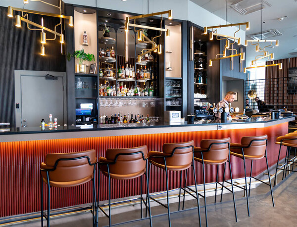 LATVIA, RIGA, MARCH, 10, 2024: Modern interior of a bar with alcoholic drinks and high bar chairs in Radisson Blu Latvija Conference and Spa Hotel, Riga. Latvia.