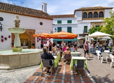 SPAIN, MARBELLA, 25, MAY, 2023: People have lunch in street cafe on Orange Square near the fountain in Marbella Old Town, Spain. clipart