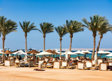 EGYPT, HURGHADA, 20, APRIL, 2024: Hurghada 'daki Steigenberger ALDAU Oteli' nde Kızıldeniz kıyılarında güneş pansiyonları ve şemsiyeli kumsal. Mısır
