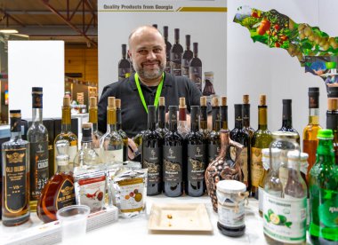 LATVIA, RIGA, 05, JUNE, 2024: A man presents various Georgian wines at the Georgia stand at a food exhibition in Riga, Latvia clipart