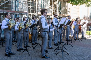 LATVIA, RIGA, 23, HAZİRAN, 2024: Riga Old Town, Letonya 'da tatil öncesi müzik stantları üzerinde müzik aletleri ve notlarla konser kostümlü bir müzik grubunun provası