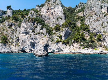 Tyrhenia Denizi, Campania, İtalya 'da volkanik kökenli Capri adasının doğal kemer ve mağaraları dikenli Akdeniz çalılarıyla kaplı kireçtaşı kayalıkları.