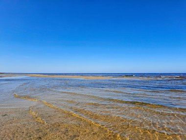 Riga, Letonya 'da güneşli bir günde küçük dalgalar ve kum tepeleriyle Baltık Denizi Panoraması. Çevre ekolojisi kavramı.