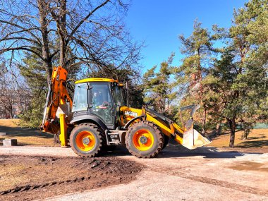 LATVIA, RIGA, MARCH, 12, 2024: Bir belediye traktörü Riga, Letonya 'da kazı çalışmalarının ardından şehir parkında çalışıyor.