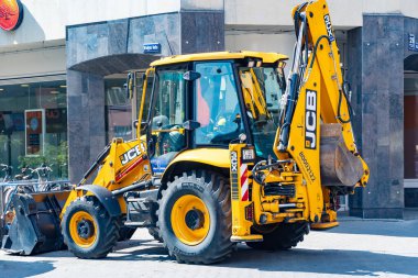 LATVIA, RIGA, 28, JULY, 2024: JCB 4CX-14 Super Backhoe Loader at city, Riga Old Town, Letonya 'nın merkezinde çalışıyor.