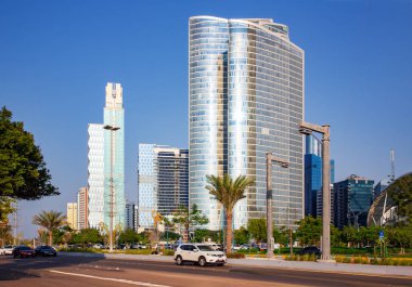 BAE, ABU DHABI, NOVEMBER, 2021 - Birleşik Arap Emirlikleri 'nin başkenti Abu Dabi' deki La Corniche gezinti alanı yakınlarında yeşil palmiye ağaçlarıyla çevrili gökdelenmiş gökdelenler.