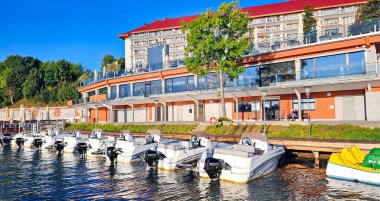 Polonya, Mikolajki, 28 Ağustos 2024: Polonya Mikolajki kasabası Golebiewski oteli yakınlarındaki tekne ve scooterlar için Marina Gölü 'nde. Polonya 'nın en büyük otel zinciri.