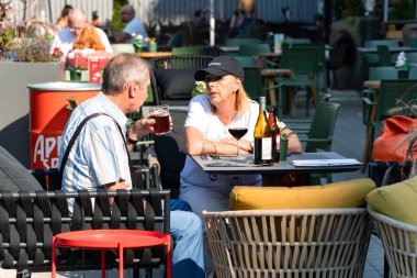 LATVIA, RIGA, SEPTEMBER, 20, 2024: Riga Old Town, Letonya 'da sıcak bir sonbahar gününde bir kafenin açık verandasında bira içen sevimli çift