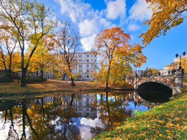 LATVIA, RIGA, 15, ECTOBER, 2024: Letonya 'nın başkenti Riga Old Town' da şehir kanalı yakınlarında yeşil çimlerle kaplı Kronvalda Parkı 'nda sonbaharın başlarında parlak renkler.