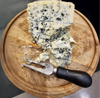 Large piece of blue cheese with carving knife on food wooden plate close-up clipart